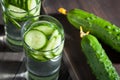 Fresh water with a cucumber in a glass bowl on a wooden table, close-up Royalty Free Stock Photo