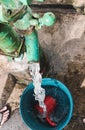 Fresh water gushes out from a deep well manual metal hand pump into a pail for bathing and other uses Royalty Free Stock Photo