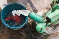 Fresh water gushes out from a deep well manual metal hand pump into a pail for bathing and other uses Royalty Free Stock Photo