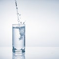 Fresh water pouring into glass on blue background Royalty Free Stock Photo