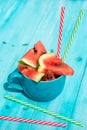 Fresh watermelon slices in a cup with coloured straws, blue wooden background Royalty Free Stock Photo