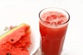 A fresh watermelon smoothie juice drink with ice cubes and a plate full of Slices of watermelon fruit cuts into pieces isolated Royalty Free Stock Photo