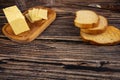 Fresh wheat bread toast and a wooden butter dish with a piece of butter and slices of cheese on a wooden background. Close up Royalty Free Stock Photo