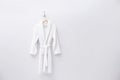 Fresh white bathrobe hanging on wall. Space for text Royalty Free Stock Photo