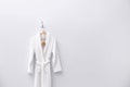 Fresh white bathrobe hanging on wall. Space for text Royalty Free Stock Photo
