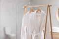 Fresh white bathrobes hanging on rack Royalty Free Stock Photo