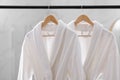 Fresh white bathrobes hanging on rack Royalty Free Stock Photo