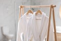 Fresh white bathrobes hanging on rack Royalty Free Stock Photo