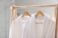 Fresh white bathrobes hanging on rack indoors Royalty Free Stock Photo