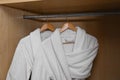 Fresh white bathrobes hanging in closet Royalty Free Stock Photo