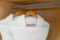 Fresh white bathrobes hanging in closet Royalty Free Stock Photo