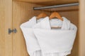 Fresh white bathrobes hanging in closet Royalty Free Stock Photo