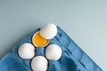 Fresh white chicken eggs in eco-packaging on a blue background. Broken egg with yolk in the shell. Farm natural products. Top view Royalty Free Stock Photo