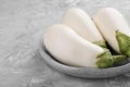 Fresh white eggplants in bowl on grey textured table, closeup. Space for text Royalty Free Stock Photo
