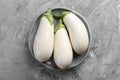 Fresh white eggplants in bowl on grey textured table, top view Royalty Free Stock Photo