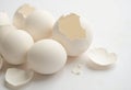 Fresh white eggs with broken shells scattered on a light background Royalty Free Stock Photo