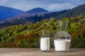 Fresh white milk in a jug and glass on wooden table with the autumn Carpathian mountains background, closeup. Dairy product Royalty Free Stock Photo