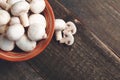 Fresh white mushrooms champignon in brown bowl on wooden background. Top view. Copy space. Royalty Free Stock Photo