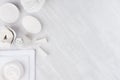 Fresh white natural cosmetics - white cream, soap, salt, towel and bath accessories on soft light white wood table, border. Royalty Free Stock Photo