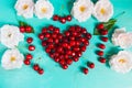 Fresh white roses with water drops, red cherry in a shape of a heart on an old painted wooden table Royalty Free Stock Photo