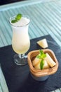 Fresh white smoothie in a glass with sliced pieces of melon and mint on a blue wooden background. Summer cool drinks Royalty Free Stock Photo