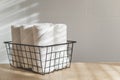 Fresh white towels rolled fluffy fabric spa textile stack in metallic basket wooden sunny tabletop Royalty Free Stock Photo