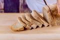 Fresh whole grain bread on kitchen table or wooden bread man holding bread knife and cutting a slice from loaf for healthy eating Royalty Free Stock Photo