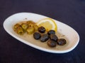 Fresh whole green and black olives with herbs, spices and lemon in a white bowl. Antipasti or wine appetizer Royalty Free Stock Photo