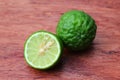 Fresh whole and half kaffir limes on wooden background