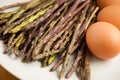 Fresh wild asparagus on a plate with eggs ready to be cooked Royalty Free Stock Photo