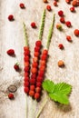 Fresh wild strawberries in three blade of grass on a old wooden surface.