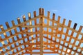 Fresh wooden yellow rafters on a background of blue sky. The construction of the pitched roof of a residential building. Bright