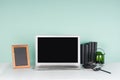 Fresh workplace for education, work with blank notebook screen, black stationery, books, candlestick, photo frame in green mint. Royalty Free Stock Photo