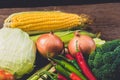 Fresh yellow corn with cobs and various kinds of vegetables as background on rustic wooden table Royalty Free Stock Photo