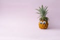 Fresh funny pineapple with googly eyes on pink background, copy space