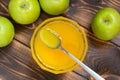 Fresh yellow honey in glass bowl with spoon inside and green apples around it Royalty Free Stock Photo