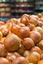 Fresh yellow onions as a background. Vegetable store. Yellow onion lies in a box in a store for sale. vertical photo Royalty Free Stock Photo