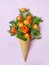 Fresh yellow-orange roses in a waffle cone on a pink background. Flat lay. Original packaging of the bouquet Royalty Free Stock Photo