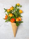 Fresh yellow-orange roses in a waffle cone on a white concrete background. Flat lay. Original packaging of the bouquet Royalty Free Stock Photo