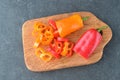 Fresh yellow and red sweet paprika cut in rings on an olive wood cutting board on a grey abstract background. Step by Royalty Free Stock Photo