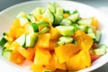 Fresh yellow tomatoes with cucumber, spices and oil in a white plate. Concept of tasty and healthy food.