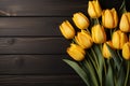 Fresh yellow tulips arranged on a white wooden backdrop, from above