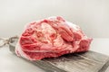 The freshest beef knuckle with bone lies on a wooden thick board on a light background. Close-up. Copy space Royalty Free Stock Photo