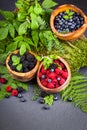 Freshly assorted berries in wooden bowl. Juicy and fresh blueberries6 blackberries and raspberries with green leaves on rustic ba Royalty Free Stock Photo