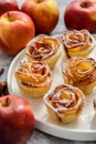 Freshly baked apple roses cakes served on white plate, flat lay