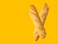 Freshly baked artisan whole french baguettes with golden crusty floury texture on yellow background