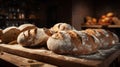 freshly baked, artisanal bread on a wooden table in a rustic kitchen, with a brick wall background, shelves, and bottles. Royalty Free Stock Photo