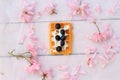 Freshly baked belgium waffles on romantic wooden table with cherry flowers