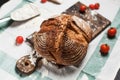 Freshly baked bread, flour and tomatoes on a wooden board on a kitchen towel on a table