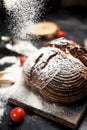 Freshly baked bread, flour and tomatoes on a wooden board on a table